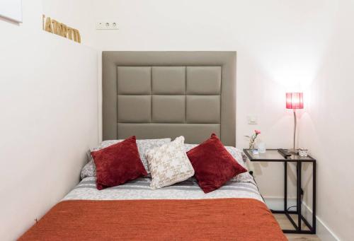 マドリードにあるApartamento en Calle Relatoresのベッドルーム1室(赤い枕とテーブル付きのベッド1台付)