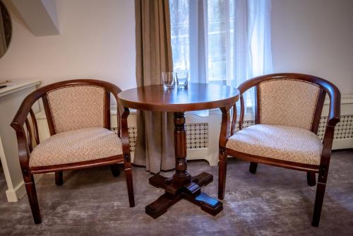a wooden table with two chairs and a table with glasses on it at Ana Boutique in Alba Iulia