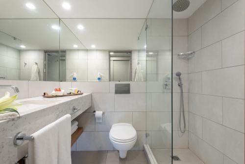 a bathroom with a toilet and a glass shower at Leonardo Club Eilat - All Inclusive in Eilat
