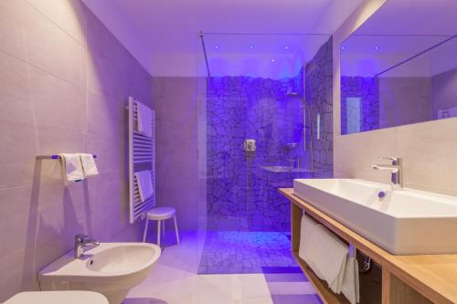 a bathroom with a sink and a shower with purple lighting at Hotel Schopfenhof in San Candido