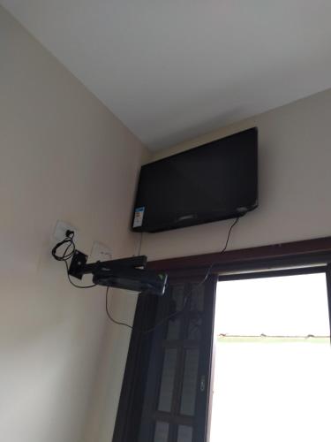 a flat screen tv on a wall above a window at Suítes Para Casal in Bertioga