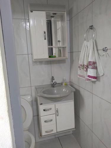 a bathroom with a sink and a toilet and a mirror at Suítes Para Casal in Bertioga