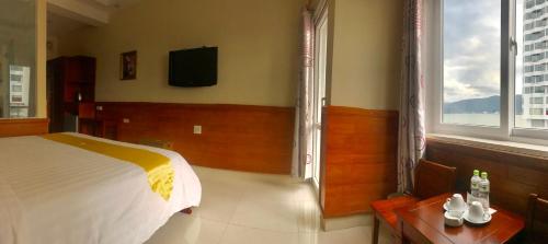 a bedroom with a bed and a table and windows at Hoang Yen Canary Hotel in Quy Nhon