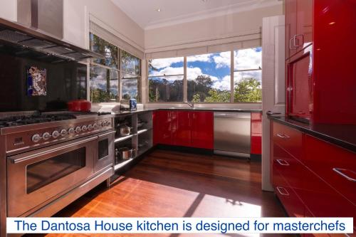 una cocina con electrodomésticos de acero inoxidable y armarios rojos en Dantosa Blue Mountains Retreat en Katoomba