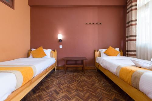 ein Hotelzimmer mit 2 Betten und einem Tisch in der Unterkunft Khangsar Home in Kathmandu