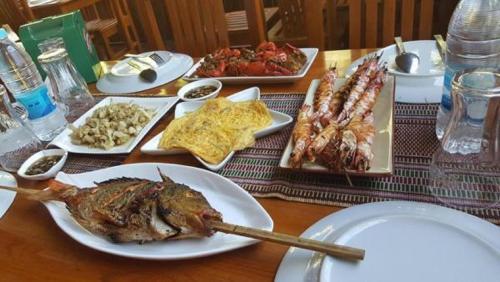 a wooden table with plates of food on it at Soe Ko Ko Beach House & Restaurant in Ngwesaung