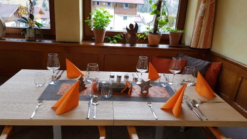 a table in a restaurant with orange napkins and glasses at Lesacherhof in Kals am Großglockner