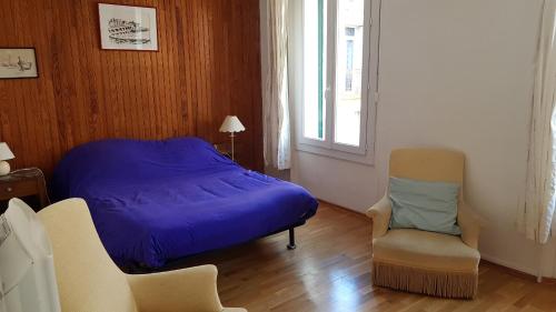 een slaapkamer met een bed, een stoel en een raam bij Rue sebastien spacious apartment close beach in Banyuls-sur-Mer