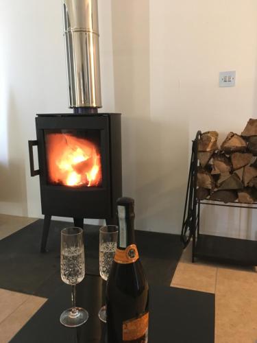 a bottle of wine and two glasses in front of a fireplace at Orchard Hideaway in Kelso