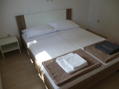 a bed with white sheets and towels on it at Apartments Lana - 30 m from the sea in Seline