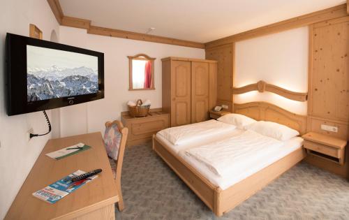 a bedroom with a bed and a desk and a television at Hotel zum grünen Tor in Tux