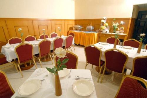 een vergaderzaal met tafels en stoelen met witte tafels en bloemen bij Royal Plaza Hotel Apartments in Dubai