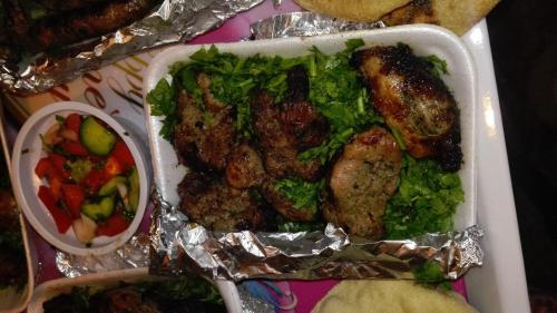 a tray of food with meat and vegetables and a salad at Aswan Nubian House in Aswan