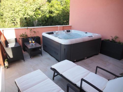 a hot tub on a patio with chairs and a table at Apartments Villa Rea in Orebić