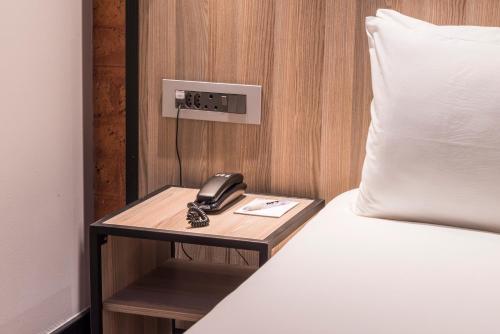 a phone on a night stand next to a bed at ONOMO Hotel Durban in Durban