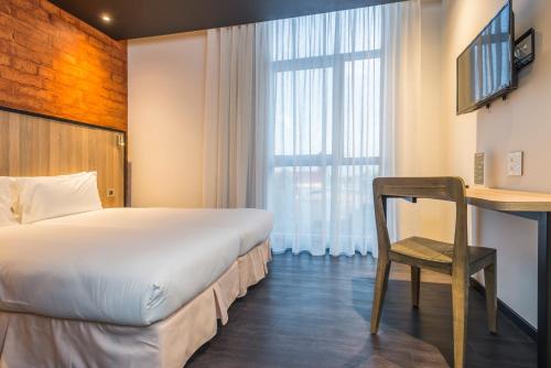a bedroom with a bed and a desk and a chair at ONOMO Hotel Durban in Durban
