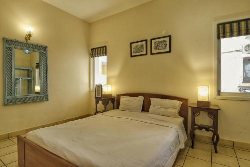 a bedroom with a bed with white sheets and a mirror at Villa Samaara1 on Candolim Main Road pool facing in Candolim