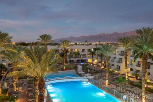 an aerial view of a resort with palm trees and a pool at Leonardo Royal Resort Eilat in Eilat