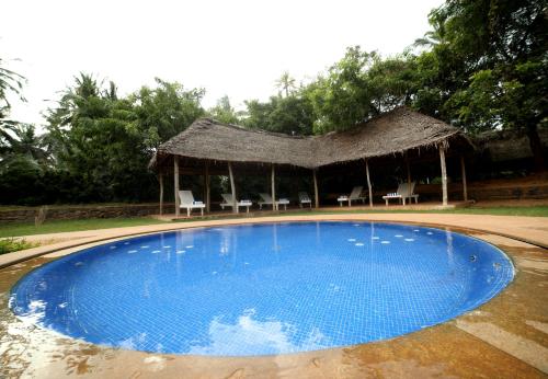 a swimming pool with a gazebo and chairs at Prince Park in Puducherry