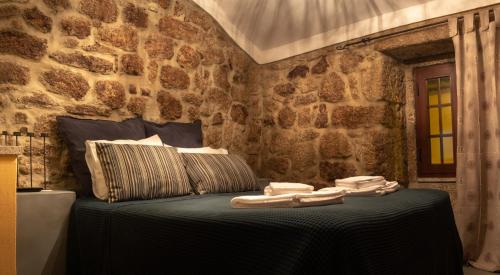 a bedroom with a bed in a stone wall at Casa dos Poetas by AL Belmonte in Belmonte