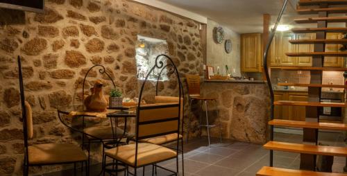 a room with a table and chairs and a stone wall at Casa dos Poetas by AL Belmonte in Belmonte
