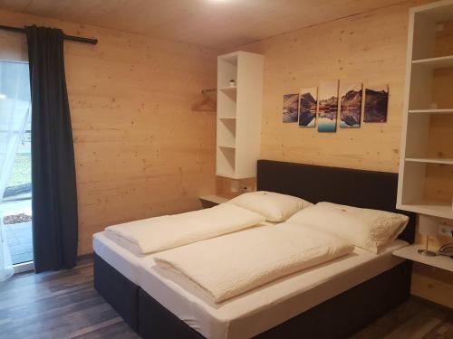 a bed in a room with a wooden wall at Gästehaus am Hahnenkamm in Reutte