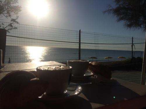 two cups on a table with a view of the ocean at Camping La Pineta in Porto Recanati