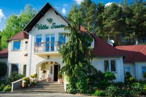 a white house with a sign on the front of it at Villa Siesta in Zielona Góra