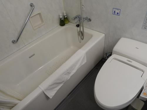 a bathroom with a white toilet and a tub and a toilet at Hotel Crown Hills Himeji in Himeji