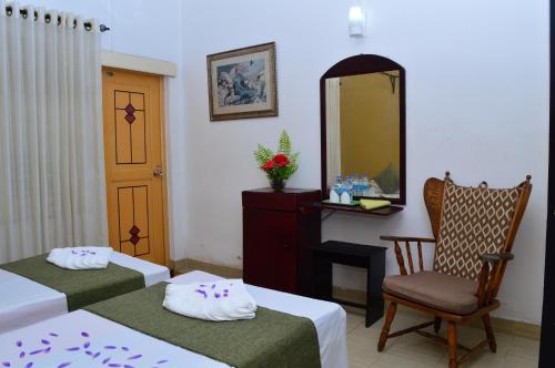 a room with two beds and a mirror and a chair at Villa Tulip Garden in Anuradhapura