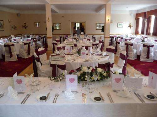 a banquet hall with white tables and chairs at Glen-Yr-Afon House Hotel in Usk
