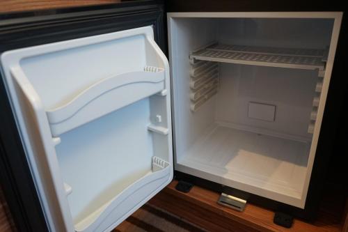 an empty refrigerator with its door open on the floor at Hotel White in Krynica Morska