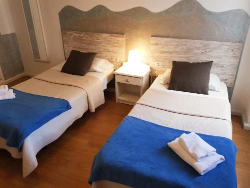 a bedroom with two beds with blue and white sheets at Hotel Horizonte in Santa Cruz de Tenerife