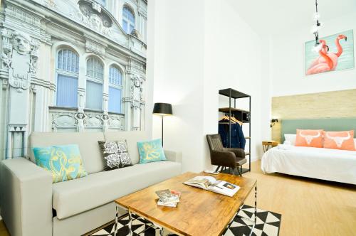 een woonkamer met een bank en een bed bij NineSuites in Sevilla