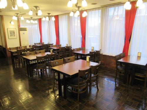 a restaurant with wooden tables and chairs and red curtains at Hotel Tomakomai Green Hills in Tomakomai