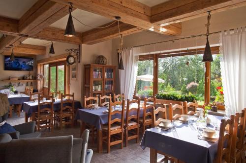 a restaurant with tables and chairs and a large window at Willa Trela in Muszyna