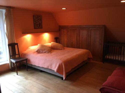 a bedroom with a bed with orange walls and a chair at Bladelijn in Lampernisse