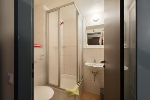 a bathroom with a shower and a toilet and a sink at meinHotel in Hamburg