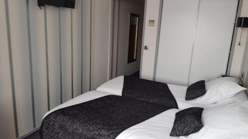 a white bed with black pillows on top of it at Hotel de Champagne in Épernay