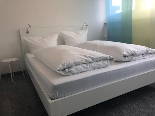 Una cama con sábanas blancas y almohadas. en Wohnung Edelweiß - Wohnen auf Zeit - Homeoffice - nah am See - buchbar ab 28 Nächte, en Schliersee
