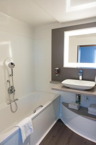 une salle de bain avec une baignoire et un lavabo dans l'établissement ibis Styles Lille Aéroport, à Lesquin