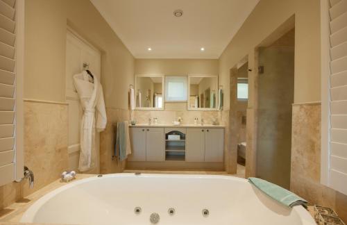 a large bathroom with a tub and a sink at La Cabriere Country House in Franschhoek