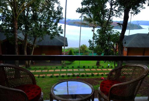 a balcony with chairs and a view of the water at LakeRose Wayanad Resort in Ambalavayal