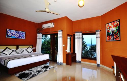 a bedroom with orange walls and a bed and windows at LakeRose Wayanad Resort in Ambalavayal