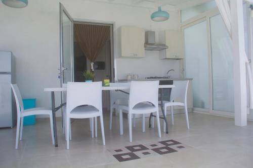 a kitchen with a table and white chairs at La Terrazza di Eraclea in San Leone
