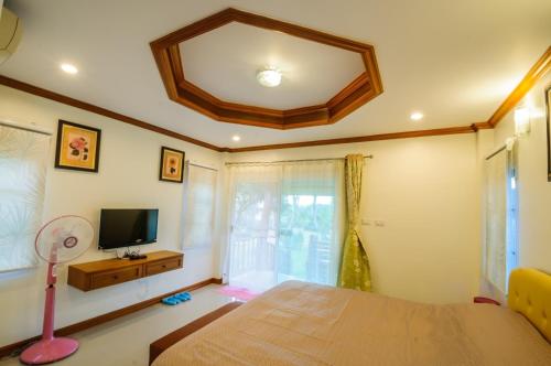 um quarto com uma cama, uma televisão e uma janela em ม่อนชมดอย em Chiang Dao