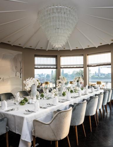 a long table in a room with chairs and a chandelier at AMERON Bonn Hotel Königshof in Bonn