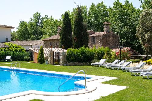 a swimming pool with lounge chairs next to a house at Els Caçadors de Maçanet in Maçanet de Cabrenys