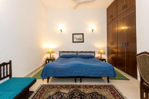 a bedroom with a blue bed and two chairs at Eleven Bed & Breakfast in New Delhi