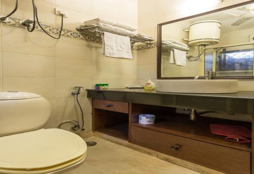 a bathroom with a toilet and a sink and a mirror at Eleven Bed & Breakfast in New Delhi